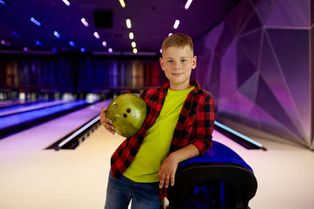 Boy with ball poses at the lane in bowling alleyの写真素材