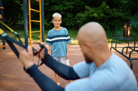 Dad and son doing exercise with ropes, playgroundの写真素材