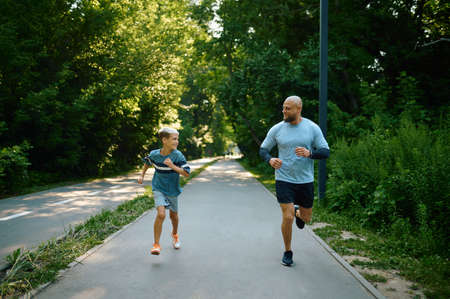 Father and son running on walking path in parkの写真素材