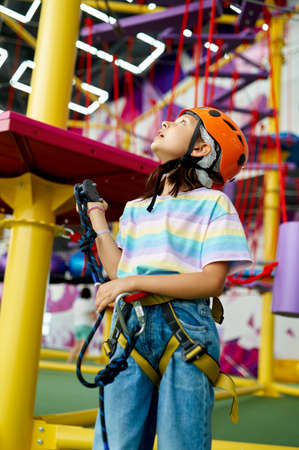 Cheerful little girl in helmet poses on zip line