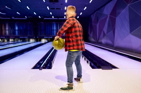 Boy holds a ball at the lane in bowling alleyの写真素材