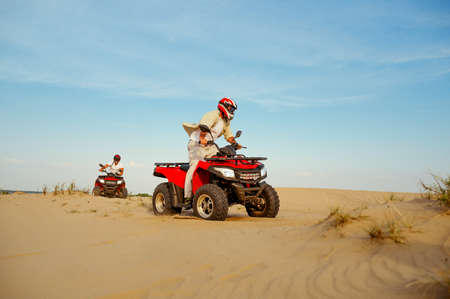 Man in helmet rides on atv in desert sands