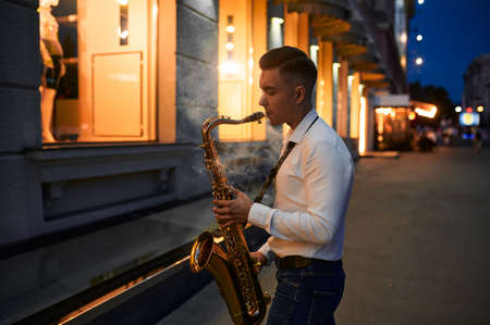 Saxophonist plays the sax on the street at nightの写真素材