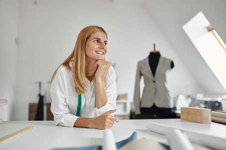 Happy dressmaker poses at workplace in workshopの写真素材