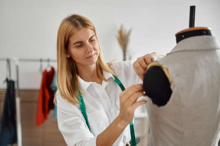 Dressmaker tries on dress on mannequin, workshopの写真素材