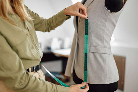 Dressmaker measures dress on mannequin in workshopの写真素材