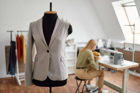 Jacket on mannequin, dressmaker at sewing machineの写真素材