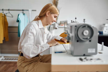 Dressmaker sews cloth on sewing machine, workshopの写真素材
