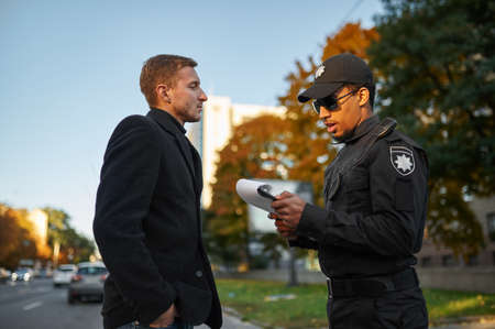 Male police officer issues a fine to driverの写真素材