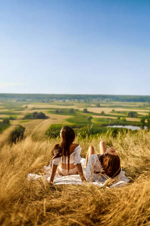Women in lingerie on blanket in field, back viewの写真素材