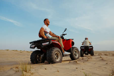 Man in helmet rides on atv in desert sands