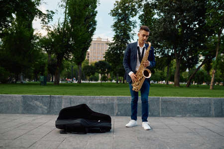 Male saxophonist plays melody in park, talentの写真素材