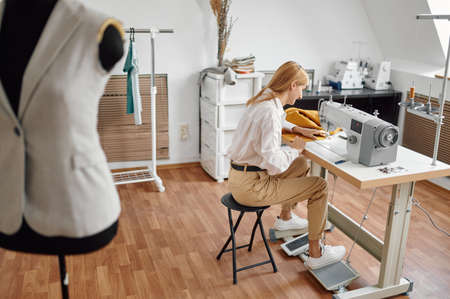 Jacket on mannequin, dressmaker at sewing machineの写真素材