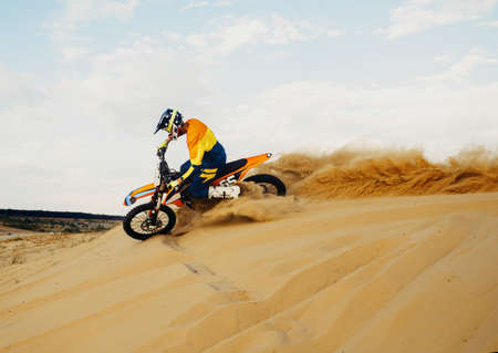 Professional motocross rider sliding down sand hillの写真素材