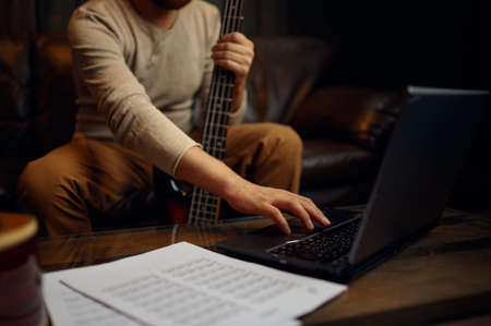 Young man learning playing guitar through internetの写真素材