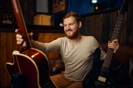 Young guitarist choosing electric or acoustic guitar