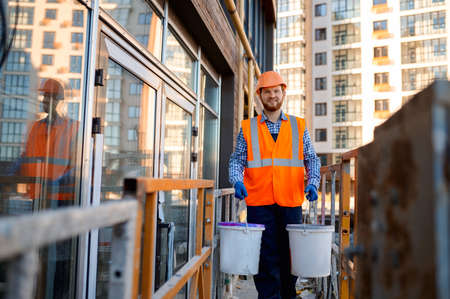 Male construction worker carrying buckets of cement