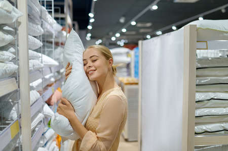 Smiling woman customer buying pillow in shopの写真素材