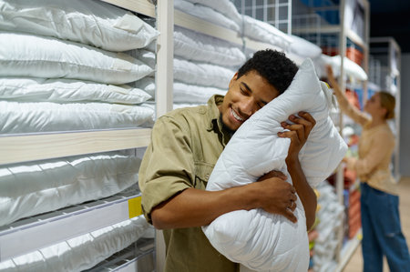 Man purchaser holding pillow in textile shopの写真素材