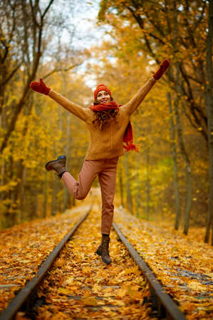Woman jumping over railroad in autumn forestの写真素材