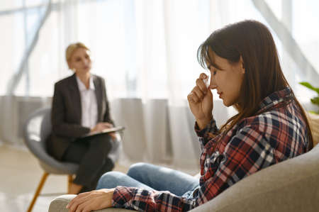 Woman crying crumpling napkins talking to psychologistの写真素材