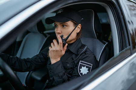 Policewoman using radio patrolling street in carの写真素材