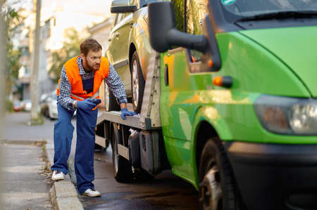 Tow truck worker checking car loading accuracy