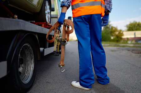 Male tow truck assistant holding fastening belts