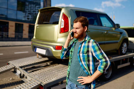 Man calling while tow truck picking up car