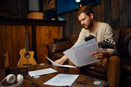 Young guy guitarist learning reading music notes