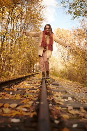 Woman balancing on railway over autumn backgroundの写真素材