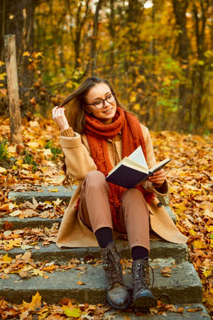 Closeup of young woman reading book outdoorsの写真素材