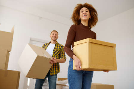 Happy multiethnic couple carrying cardboard box together
