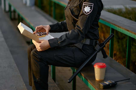 Police officer eating donut in park closeupの写真素材