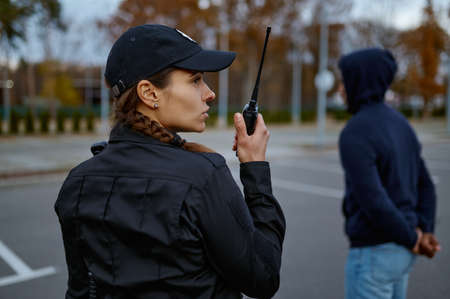 Woman cop using portable radio back viewの写真素材