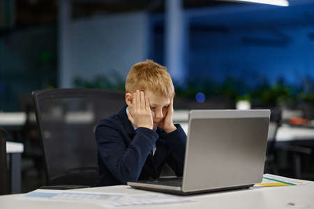 Portrait of tired businesskid working with laptopの写真素材