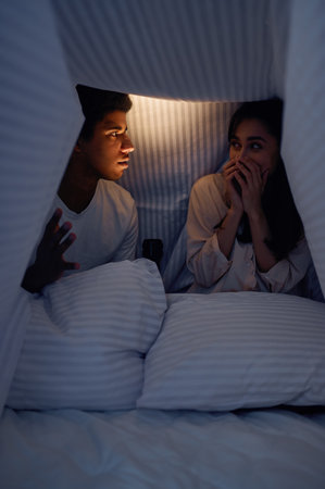 Husband telling wife scary story for under blanket
