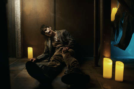 Tired and exhausted zombie sitting on floor