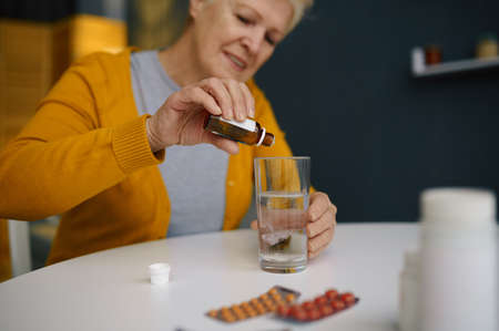 Retired elderly woman dripping medical sedative dropsの写真素材