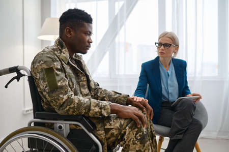 Paraplegic soldier in wheelchair talking with therapistの写真素材