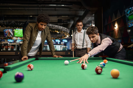 Company of handsome young guy playing in poolの写真素材