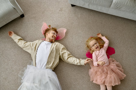 Funny dressed father and daughter lying on floorの写真素材