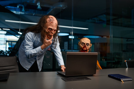 Zombie employees looking laptop and talking in night officeの写真素材