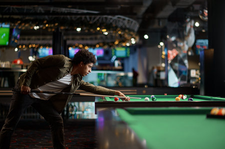 Portrait of young man preparing billiards cue