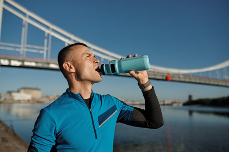 Portrait of athletic middle aged man holding water bottle for refreshing