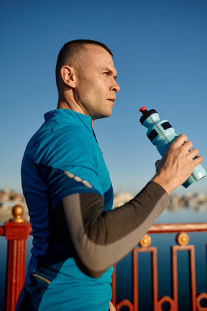 Portrait of athletic middle aged man holding water bottle for refreshingの写真素材