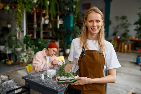 Portrait of young woman florist presenting beautiful floral compositionの写真素材