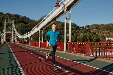 Attractive fit man running fast along the bridge
