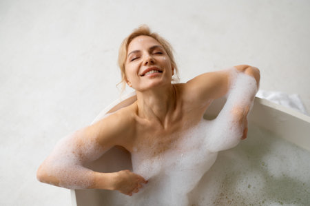 Joyful woman enjoying rest and relax in bath during home spa on weekend