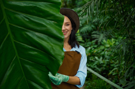 Portrait of beautiful woman gardener looking at camera through lush foliageの写真素材